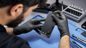 Teknisyenin iPhone 15 ekran parçası ve üst sensör alanını dikkatle incelediği premium servis sahnesi