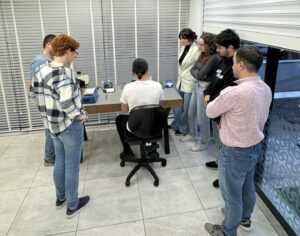 FP Akademi arşivinde çalışma tezgâhı çevresinde uygulamayı izleyen katılımcılar