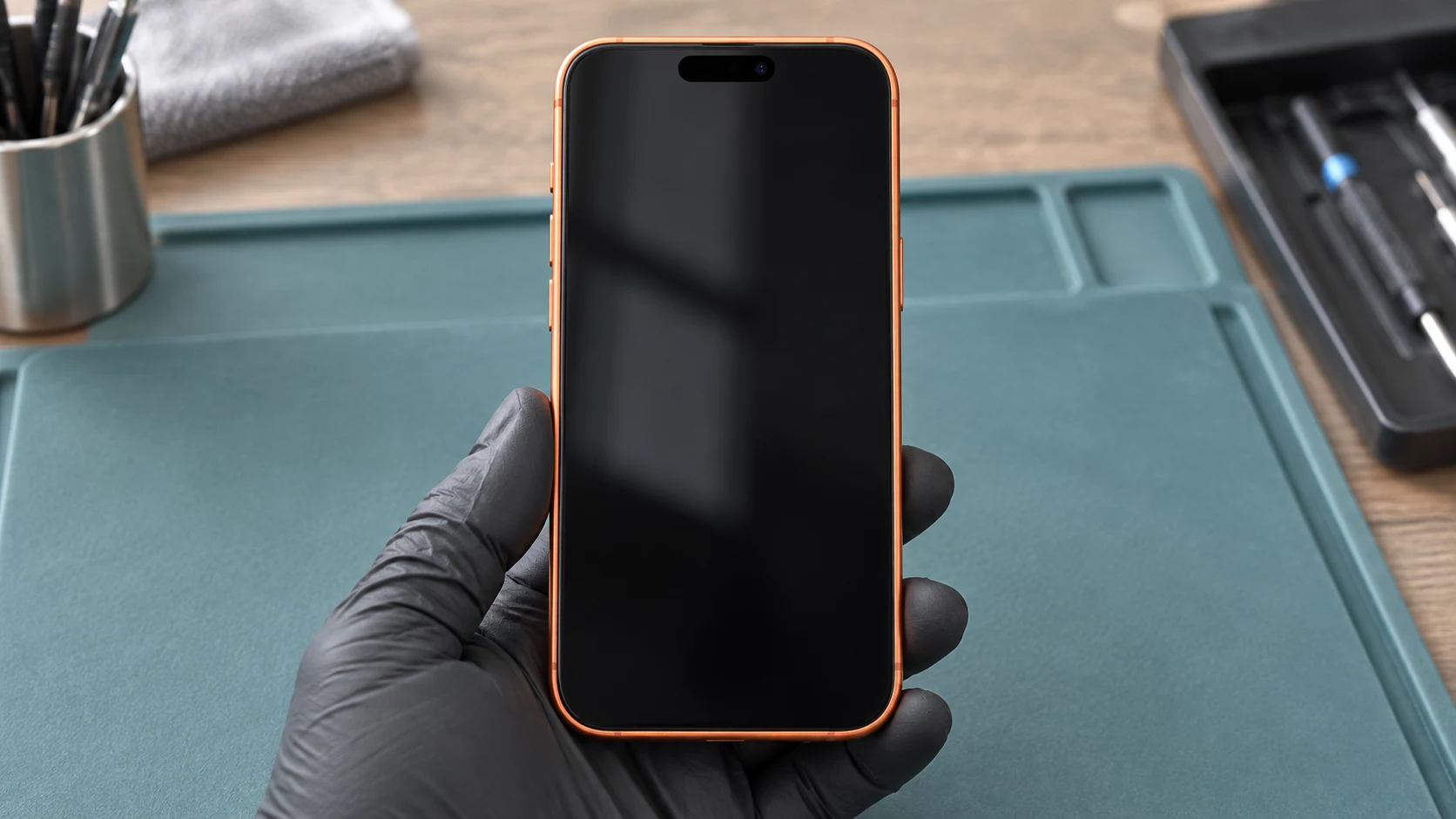 Eldivenli teknisyenin elinde dış yüzeyi incelenen kozmik turuncu telefon